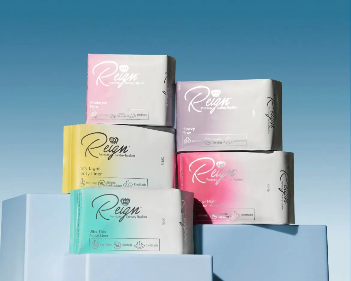 A stack of Reign sanitary napkin packs in soft pastel colors